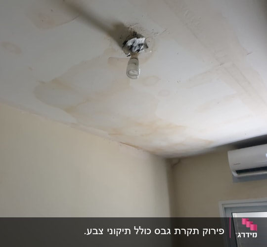 תקרה עם כתמי רטיבות ונורה חשופה